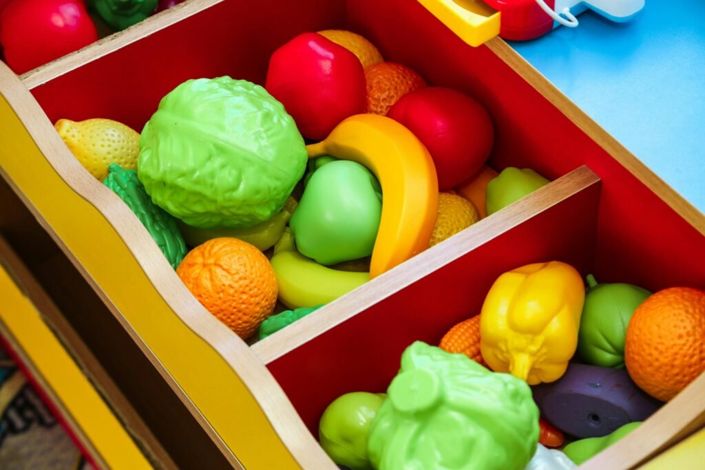 Vibrant display of toy fruits and vegetables in a wooden drawer, offering playful learning for children.