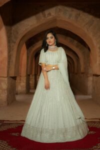 A woman in a white dress standing in an ancient arched corridor, exuding elegance and grace.