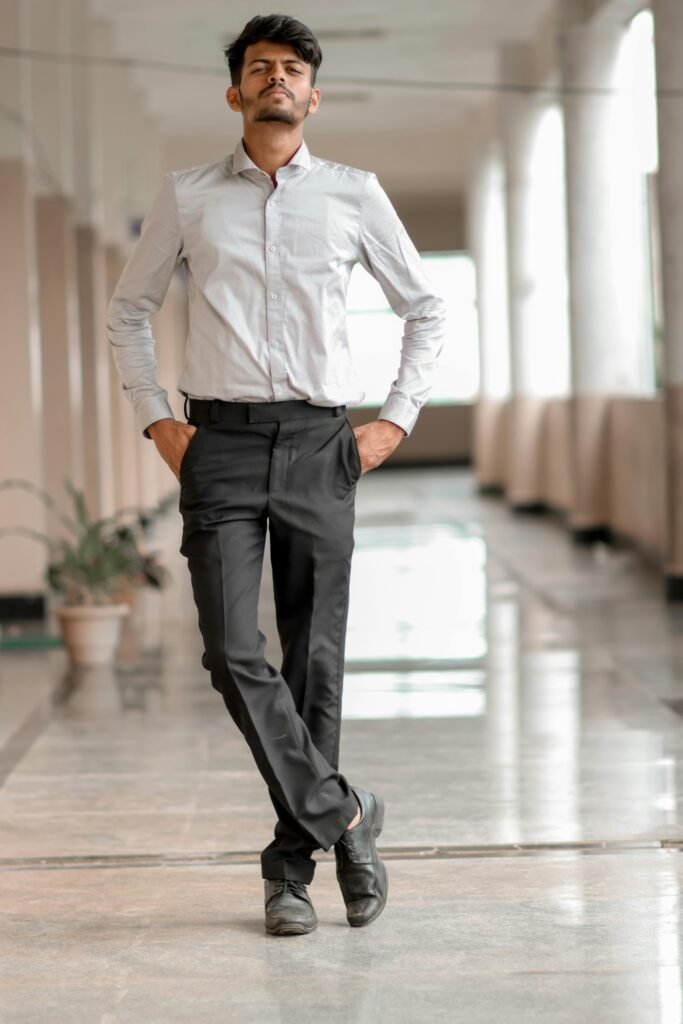 A confident man in formal attire posing in a bright hallway.
