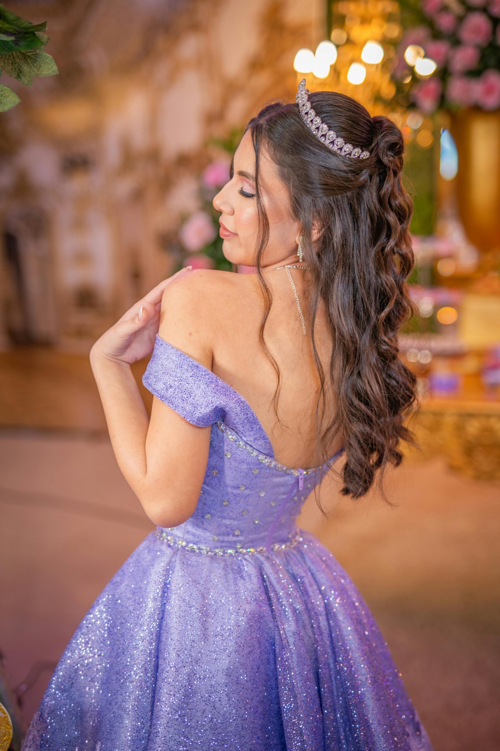 Teen girl in a lavender gown and tiara celebrating her quinceanera indoors.