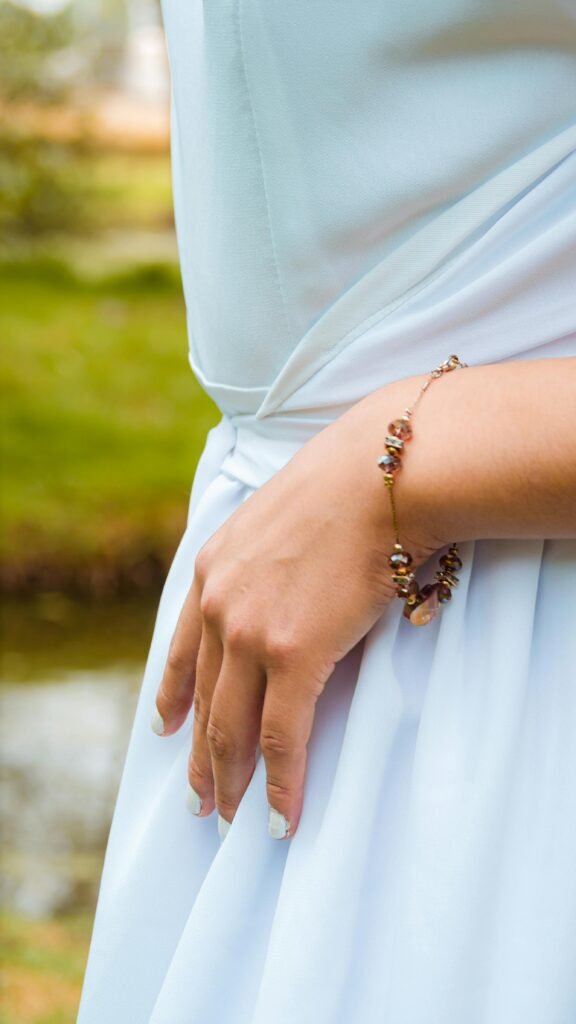 Close-up of an elegant woman's hand wearing a bracelet in a serene park setting.