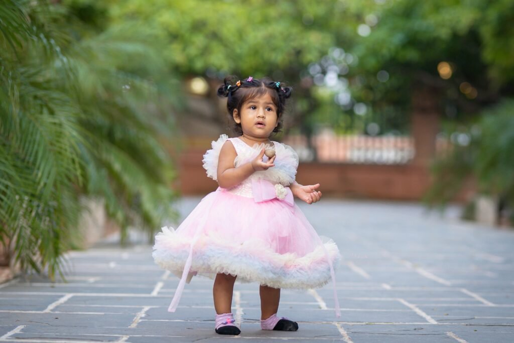Cute toddler girl in a pink dress playing outdoors.