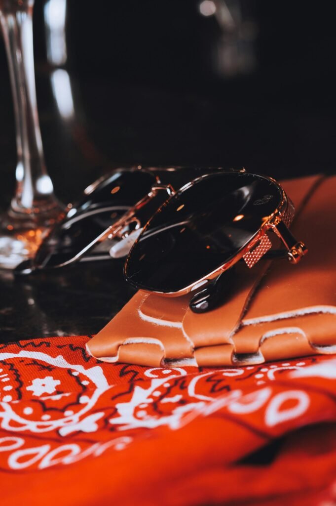 Chic sunglasses resting on a leather case with a red bandana, elegant setup.