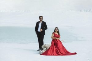 Couple posing in stylish attire against a stunning snowy background, showcasing elegance and style.