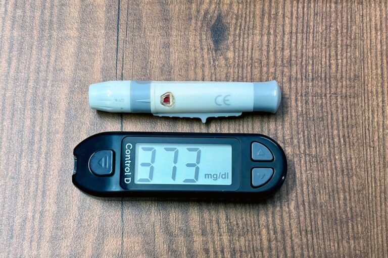 A digital glucometer and lancing device on a wooden surface indicating high blood glucose level.