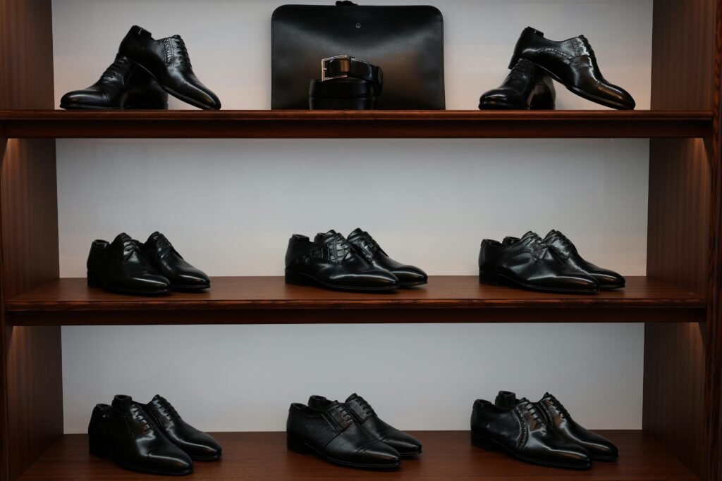 A stylish display of black leather shoes and accessories on wooden shelves in a store.