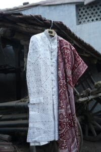 Elegant white sherwani with intricate red dupatta design, perfect for weddings.