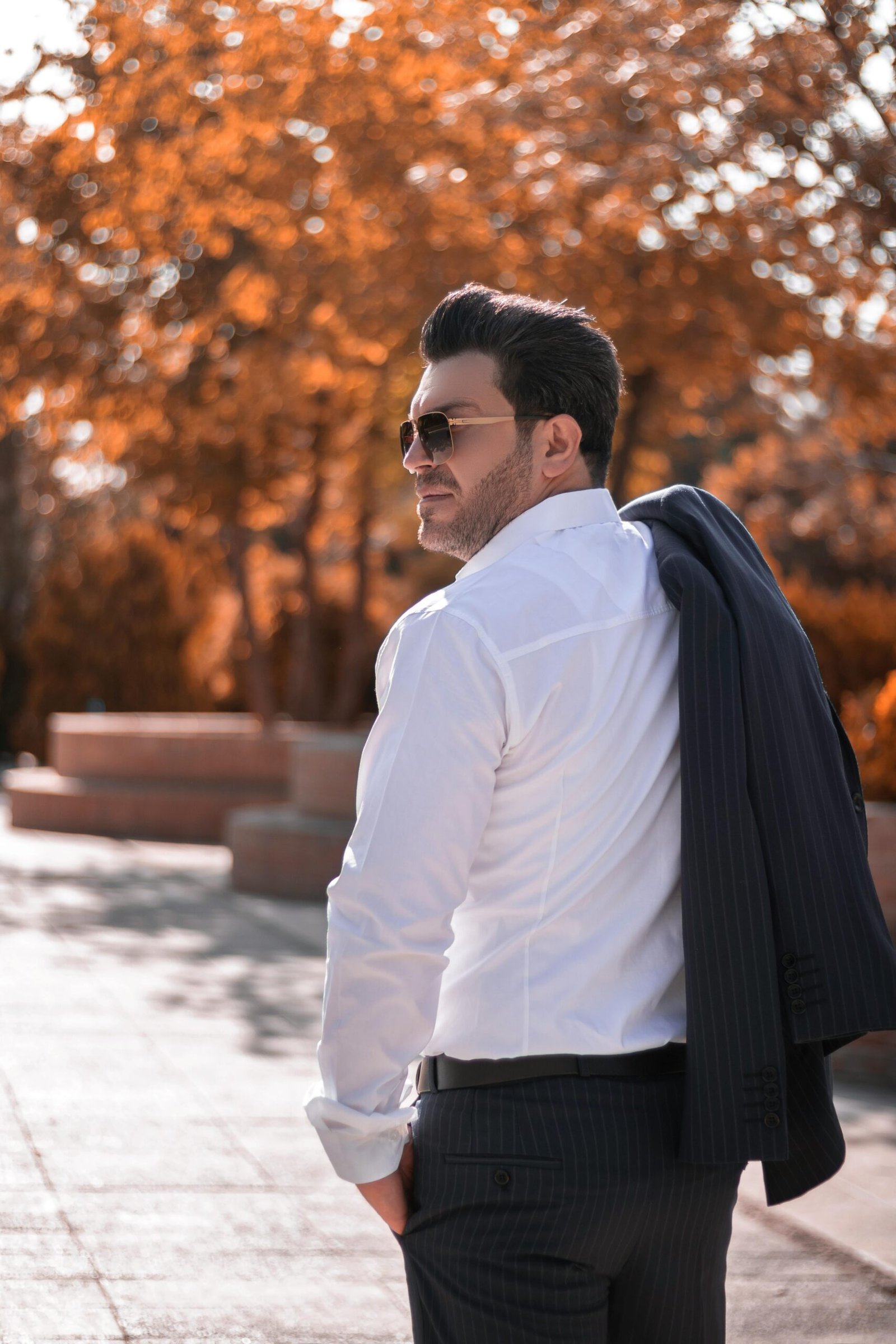 Confident man in white shirt and sunglasses walking outside in Tehran, Iran.